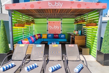 A hotel lobby with a green artificial lawn, colorful seating areas, and banners advertising the hotel. at Planet Hollywood Resort & Casino
