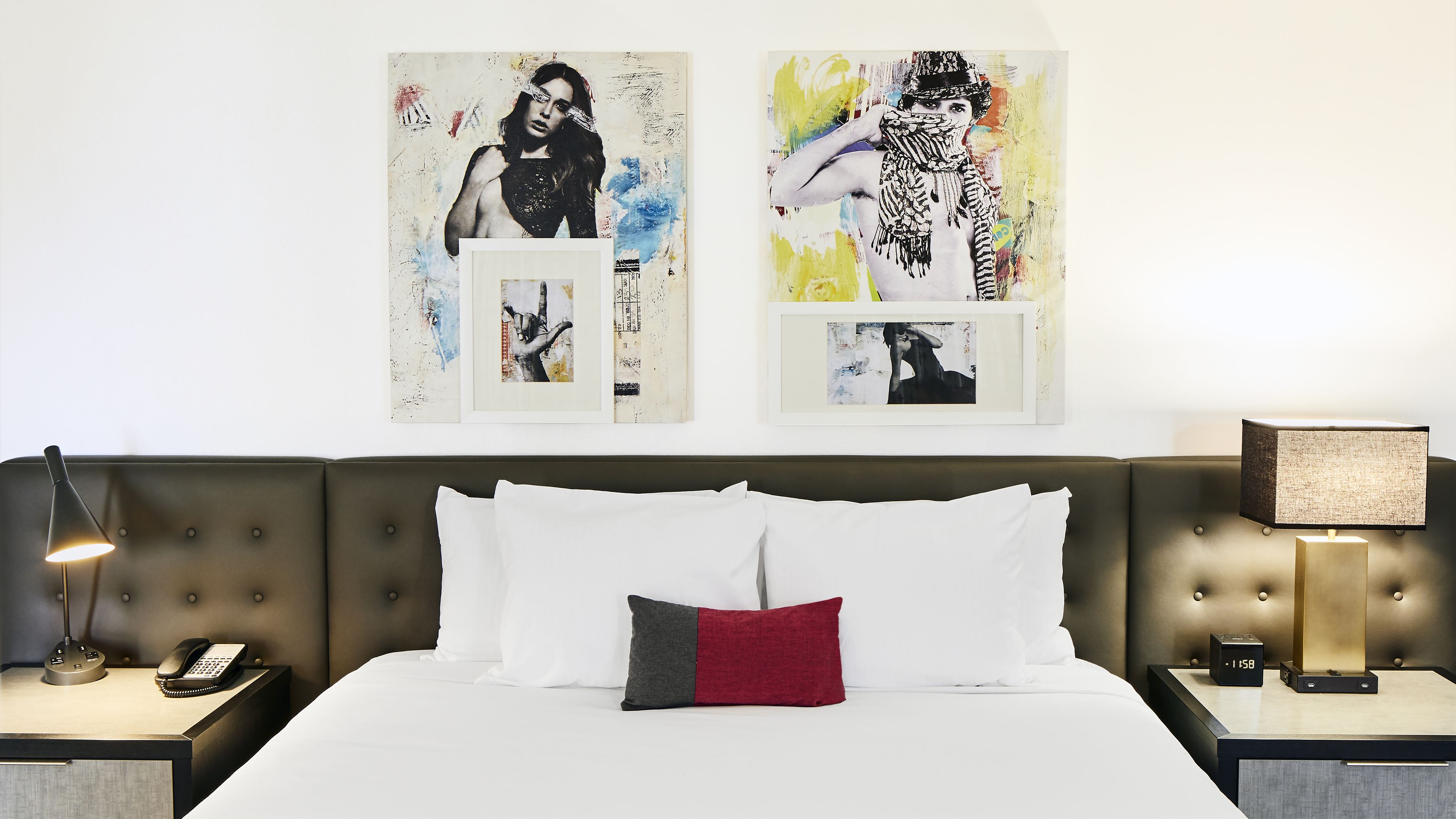 Une chambre d’hôtel avec un lit, deux tables de chevet, une lampe, un téléphone et des œuvres d’art accrochées au mur.