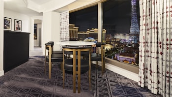 A modern room with a wooden ceiling, a grey sofa with colorful pillows, a small table with a fruit bowl and bottles, and a wall with a geometric pattern. at Planet Hollywood Resort & Casino