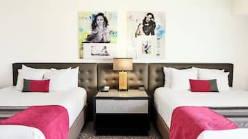 A hotel room with two beds, a nightstand with a lamp, and artwork on the wall.
