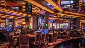 A casino interior with multiple gaming tables, chairs, and slot machines. - Planet Hollywood Resort & Casino (Las Vegas)