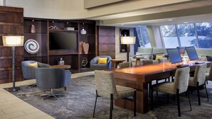 A modern hotel lobby with a large wooden reception desk, comfortable seating, a flat-screen TV, and a large window offering a view of the outdoors. - Marriott Albuquerque (Albuquerque)
