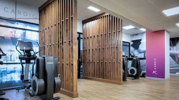 A gym with cardio equipment, wooden partitions, and a 'CARDIO' sign.