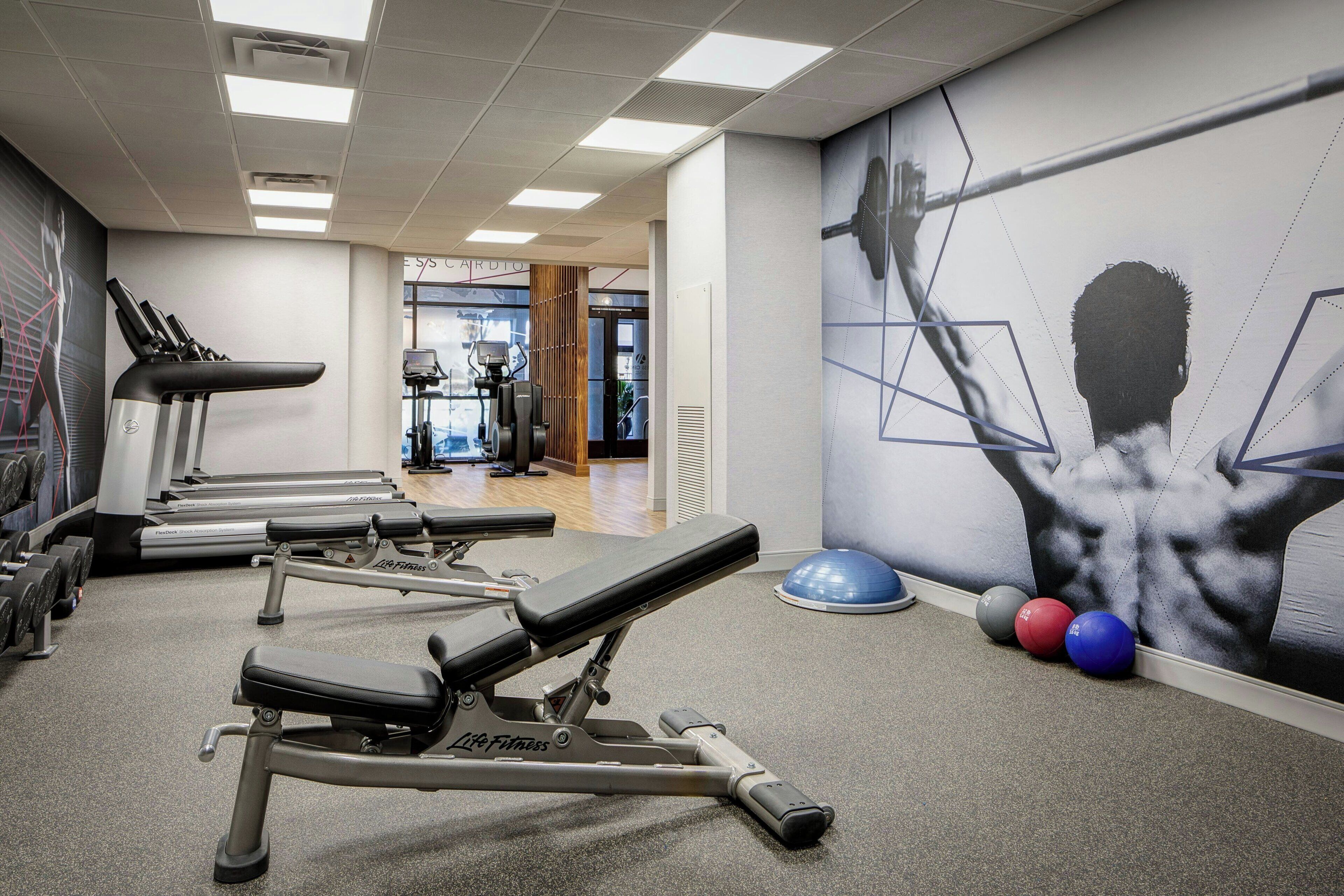 A gym with treadmills, a bench press, and exercise balls.