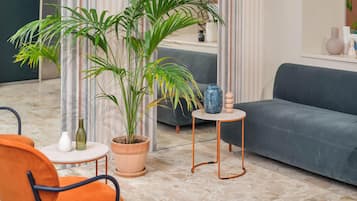 Una sala de estar moderna con un sofá gris, un sillón naranja, una mesa de centro redonda y una planta grande en maceta.