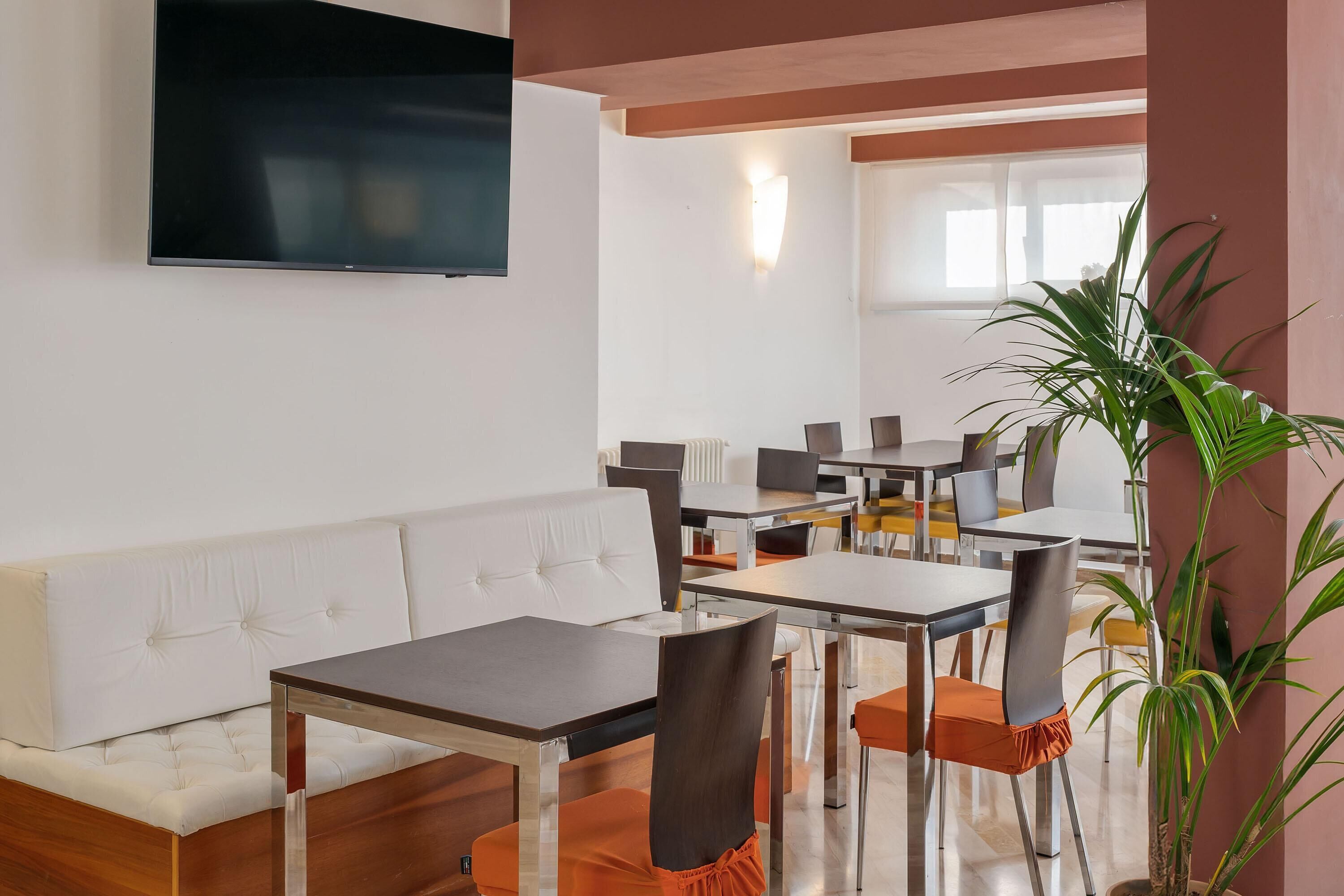 Un comedor moderno con un sofá blanco, varias mesas y sillas.