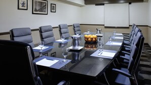 A conference room with a long table, multiple chairs, and a projector screen. - Four Points by Sheraton Detroit Novi (Novi)