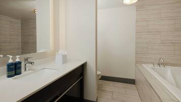 Een moderne badkamer met een witte wastafel, twee lotions, een spiegel en een bad.