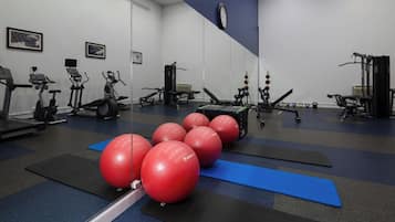 A gym with exercise equipment, red exercise balls, and blue mats.