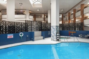 Zona de piscina con piscina azul, puesto de socorrista y señal de advertencia.