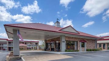 A hotel with a covered outdoor area, a brick facade, and a red roof.