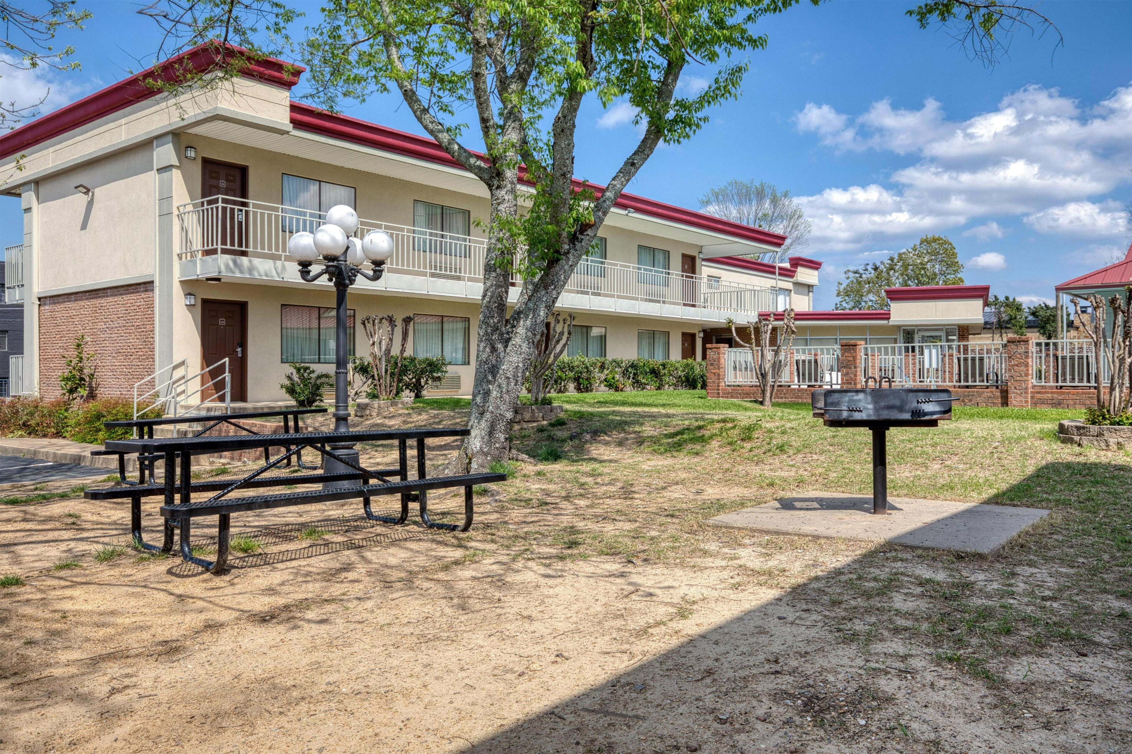 A multi-story hotel with a red roof, a picnic table, and a mailbox.