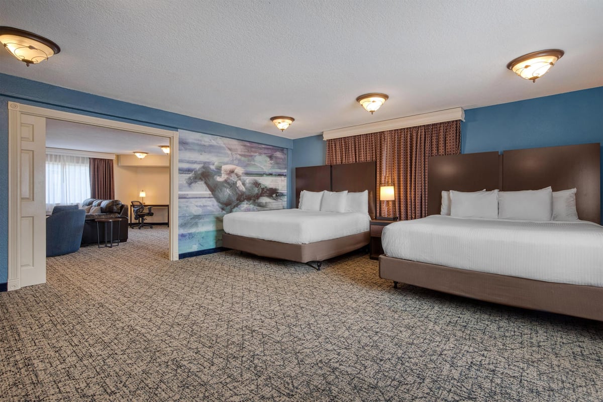 A hotel room with two beds, a painting, a desk, and a chair.