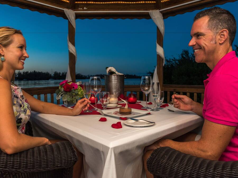 A couple dining at an outdoor table with a view of the water.