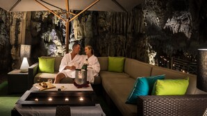A couple seated on a sofa in a cave-like interior with a table, candles, and a bottle of champagne. - Grotto Bay Beach Resort (Hamilton Parish)