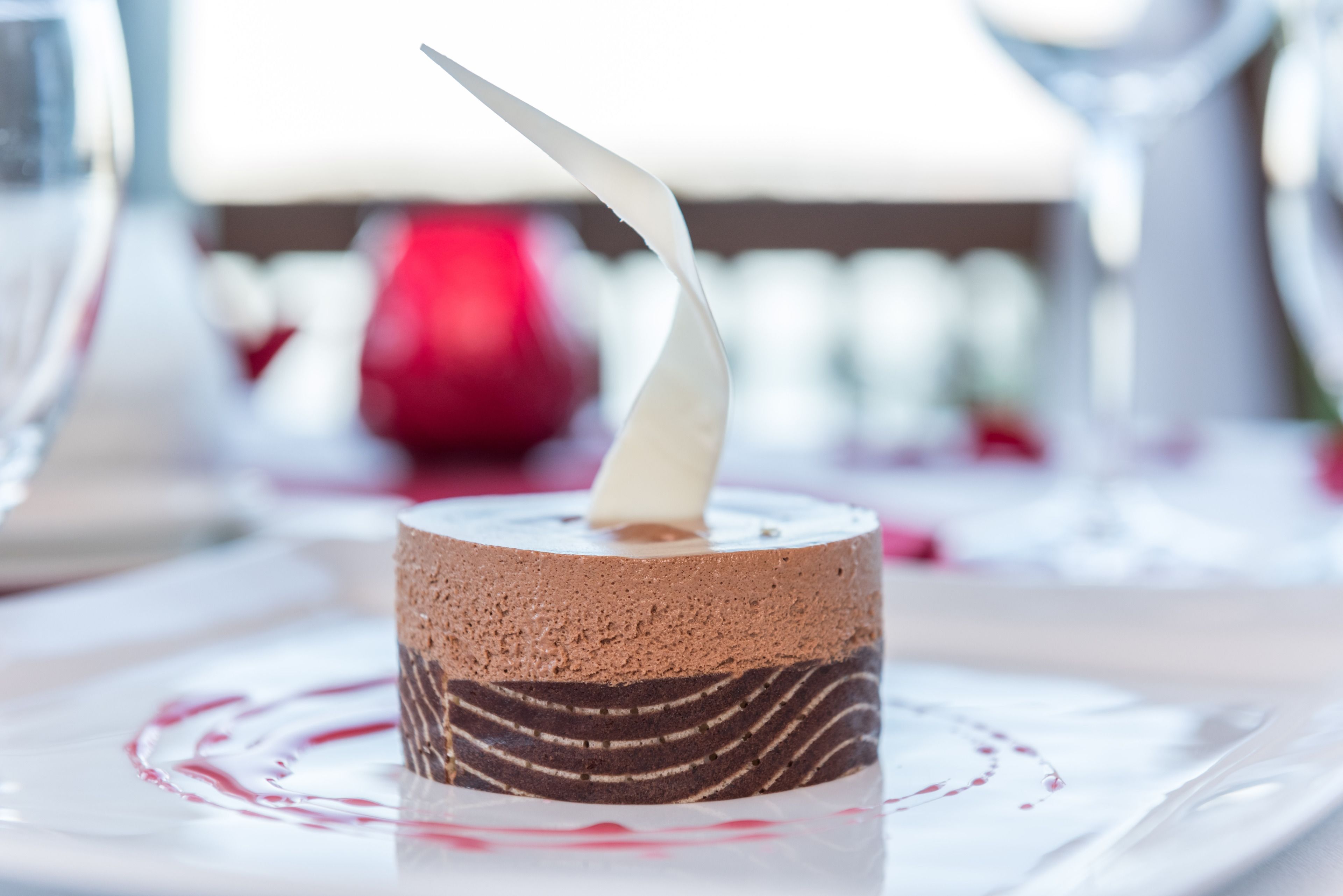 A dessert with a white cream on top, placed on a white plate with a red pattern around it.