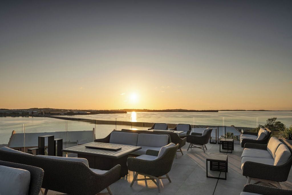 Une terrasse sur le toit, avec des sièges en plein air et une vue sur le coucher de soleil sur l’eau.