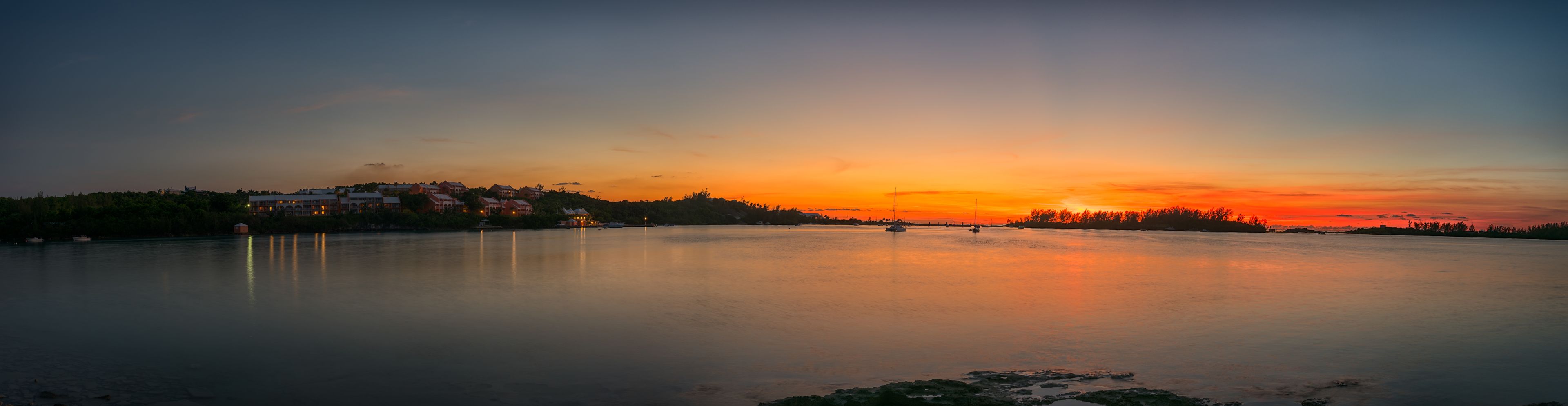 Un lago tranquilo al atardecer con edificios en la orilla.