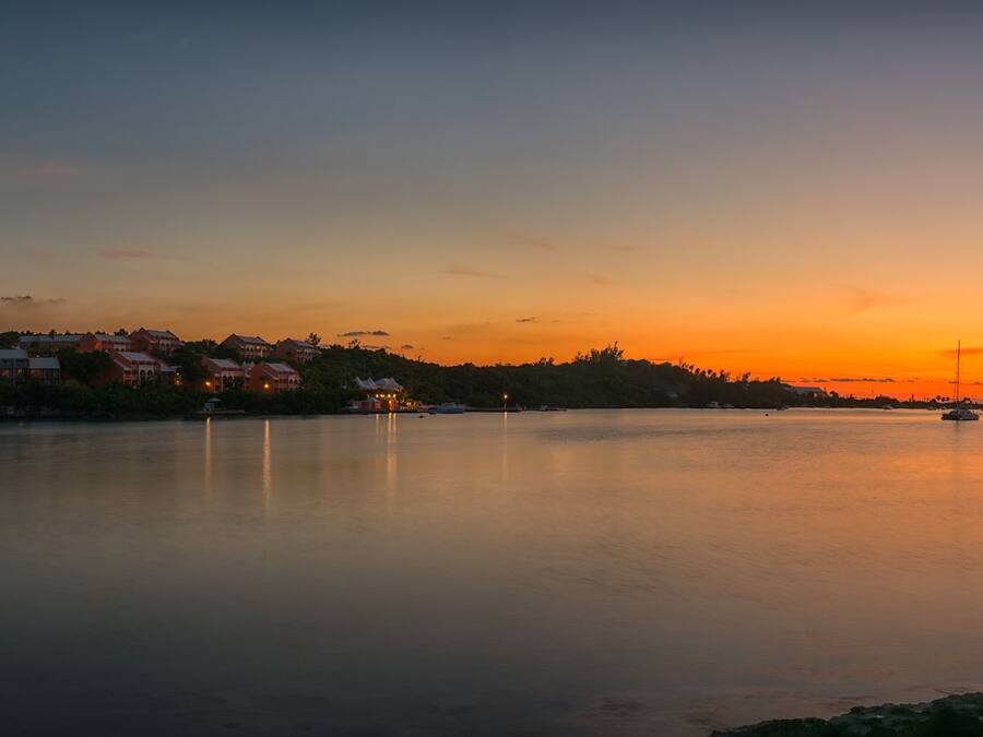 Un lago tranquilo al atardecer con edificios en la orilla.