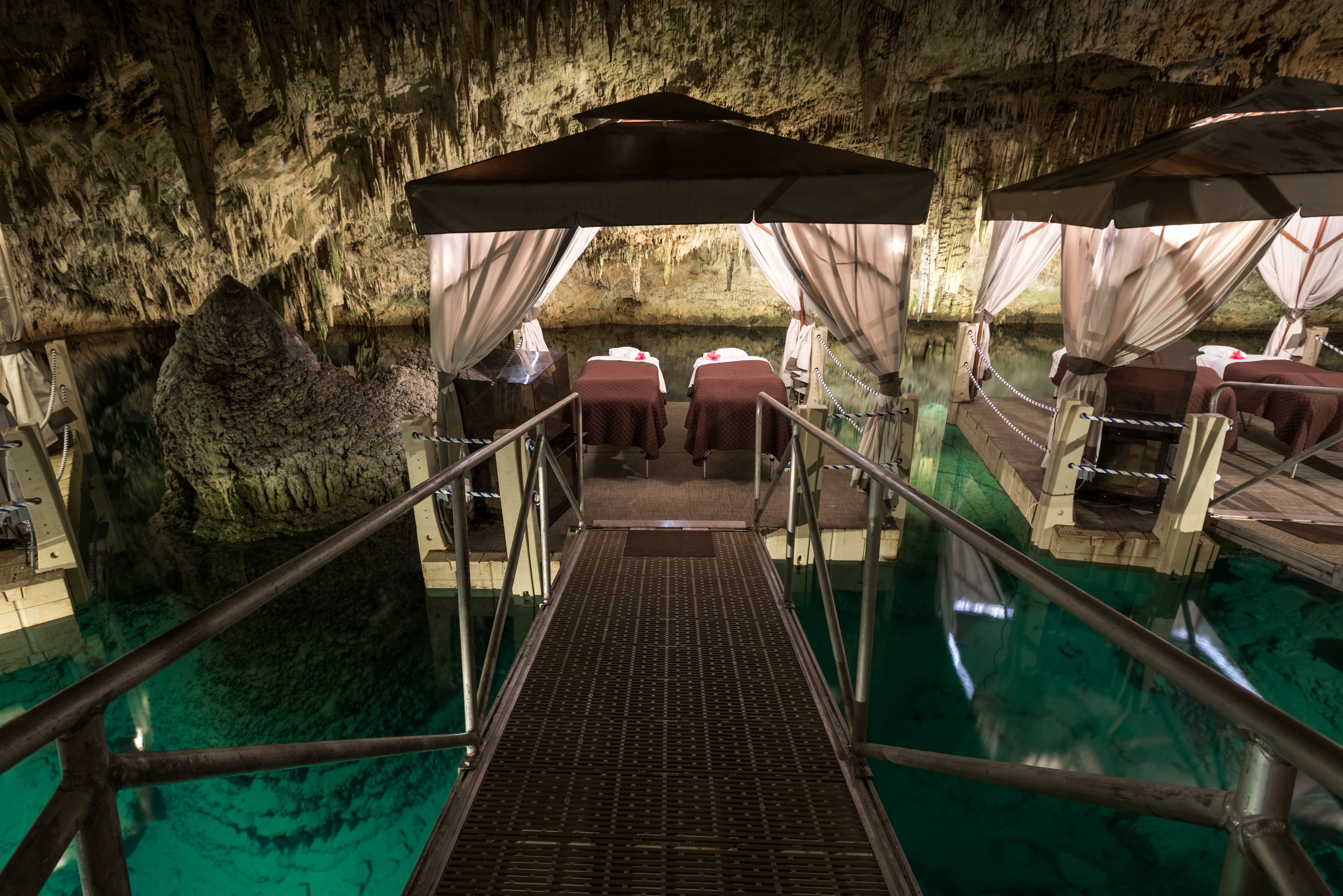 A cave-themed hotel room with a glass floor, a large rock formation, and a pool.