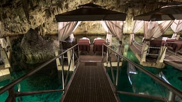 A cave-themed hotel room with a glass floor, a large rock formation, and a pool.