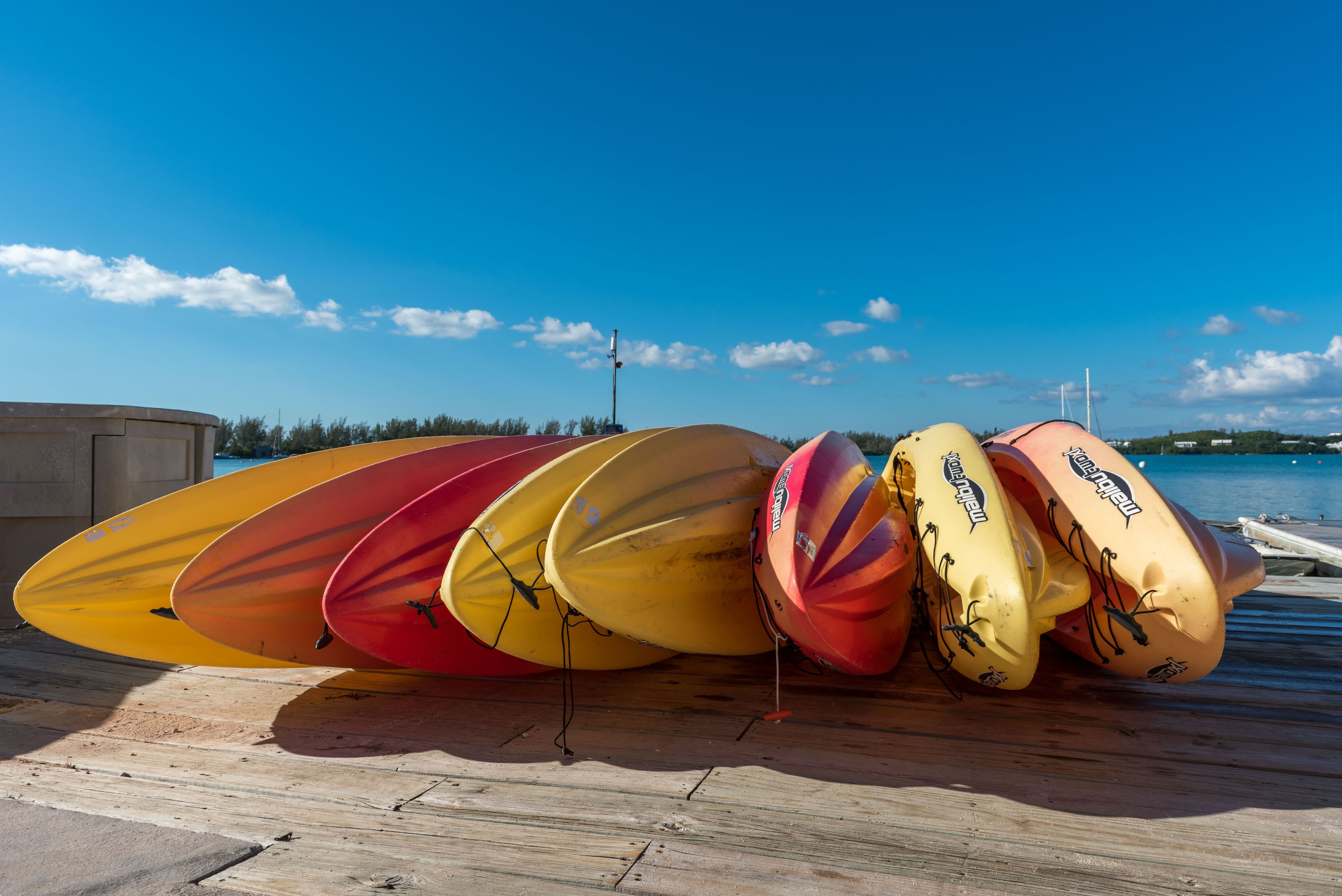 Kayaks alineados en un muelle de madera junto a un cuerpo de agua.