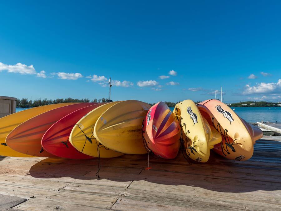 A row of kayaks on a wooden dock by a body of water.
