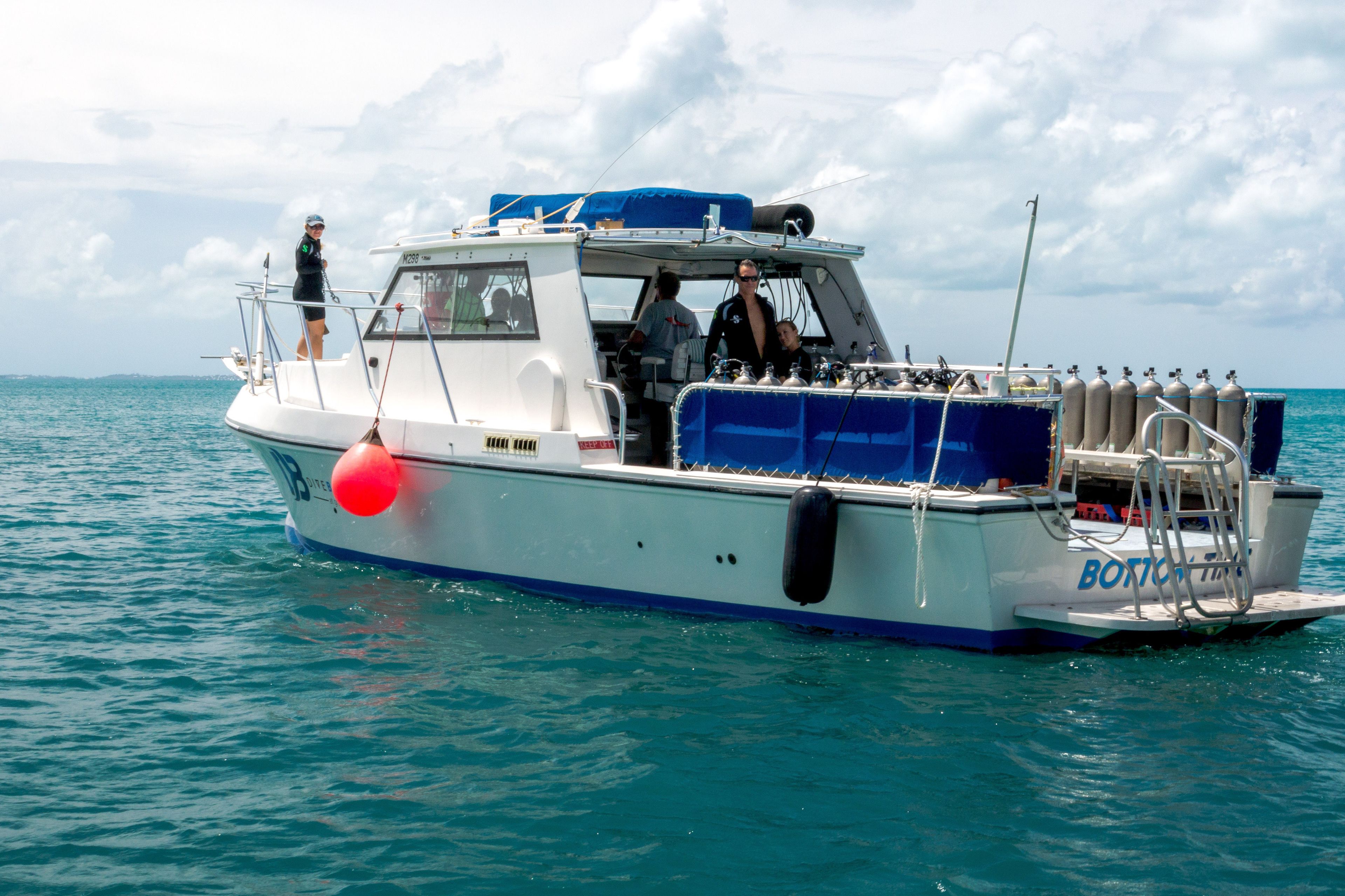 A boat with a cabin, seating area, and a blue cover on the deck.