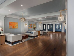 A spacious living room with hardwood flooring, a sofa set, a coffee table, and a chandelier.