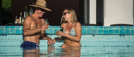A man and a woman in a swimming pool with tiled walls.