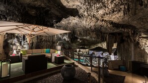 Un interior con temática de cueva, con un sofá, sillas y un parasol grande.