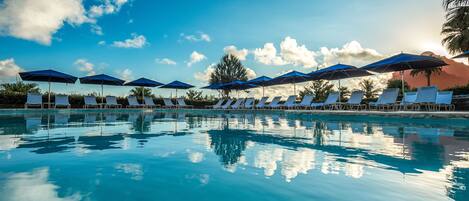 A poolside area with lounge chairs and umbrellas under a clear sky.