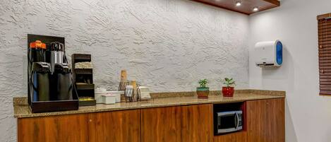 Una cocina con encimera de madera, cafetera, microondas y una planta en maceta.