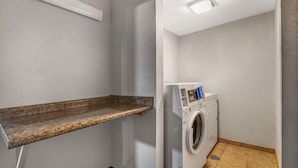 A laundry room with a washing machine, a countertop, and a ceiling light.