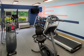 A gym with cardio equipment, dumbbells, and a treadmill.