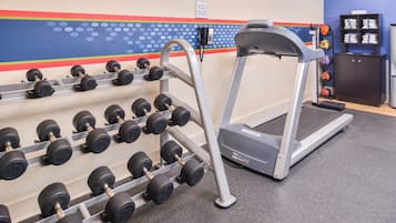 A gym with a treadmill, dumbbells, and a wall clock.