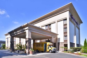 A hotel with a covered entrance, a yellow delivery truck, and a clear blue sky.