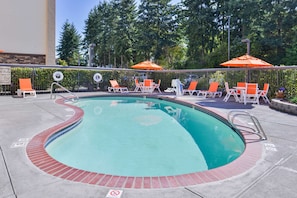 Una piscina al aire libre de temporada, sombrillas