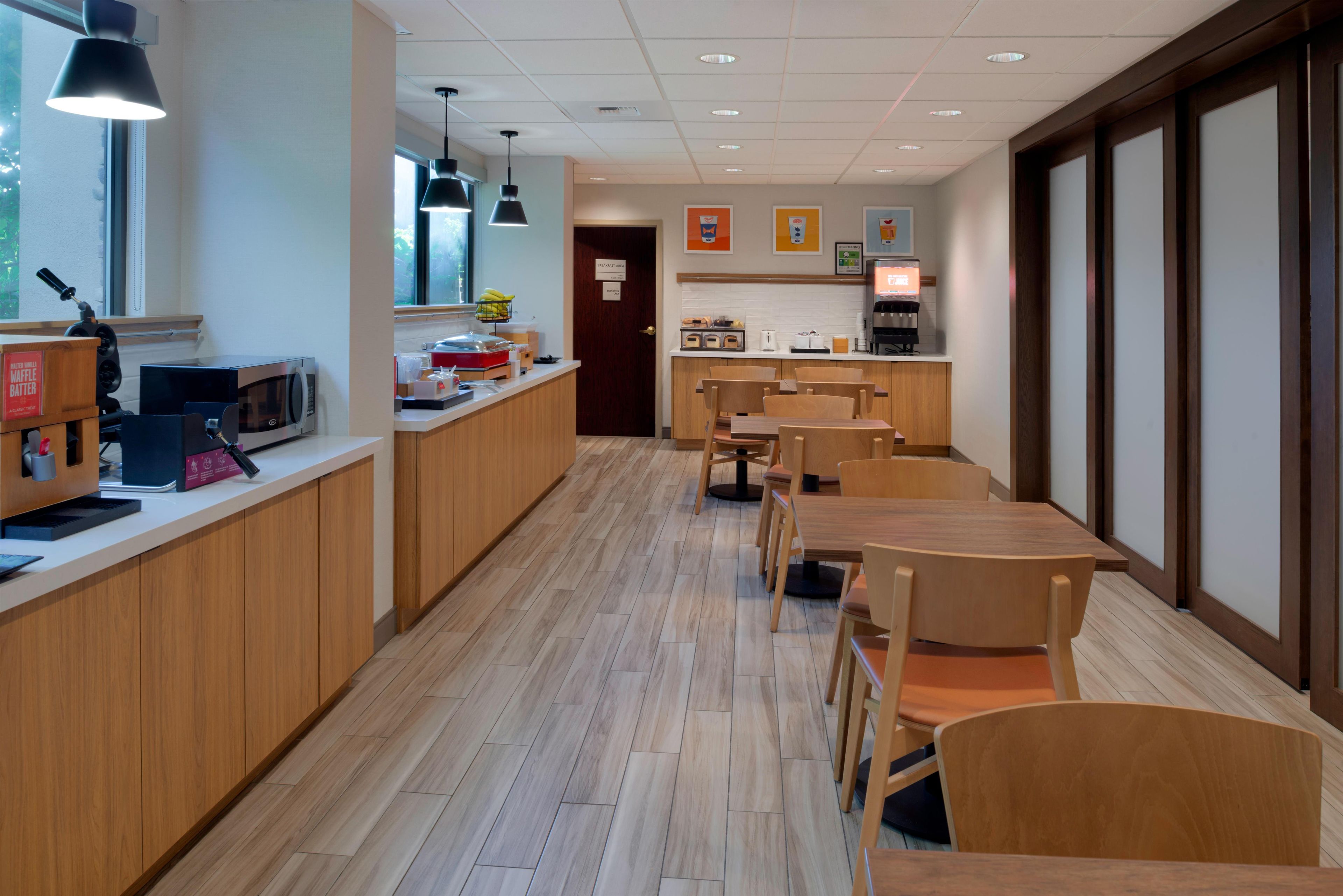 A modern dining area with wooden furniture, a counter with a microwave, and a coffee machine.