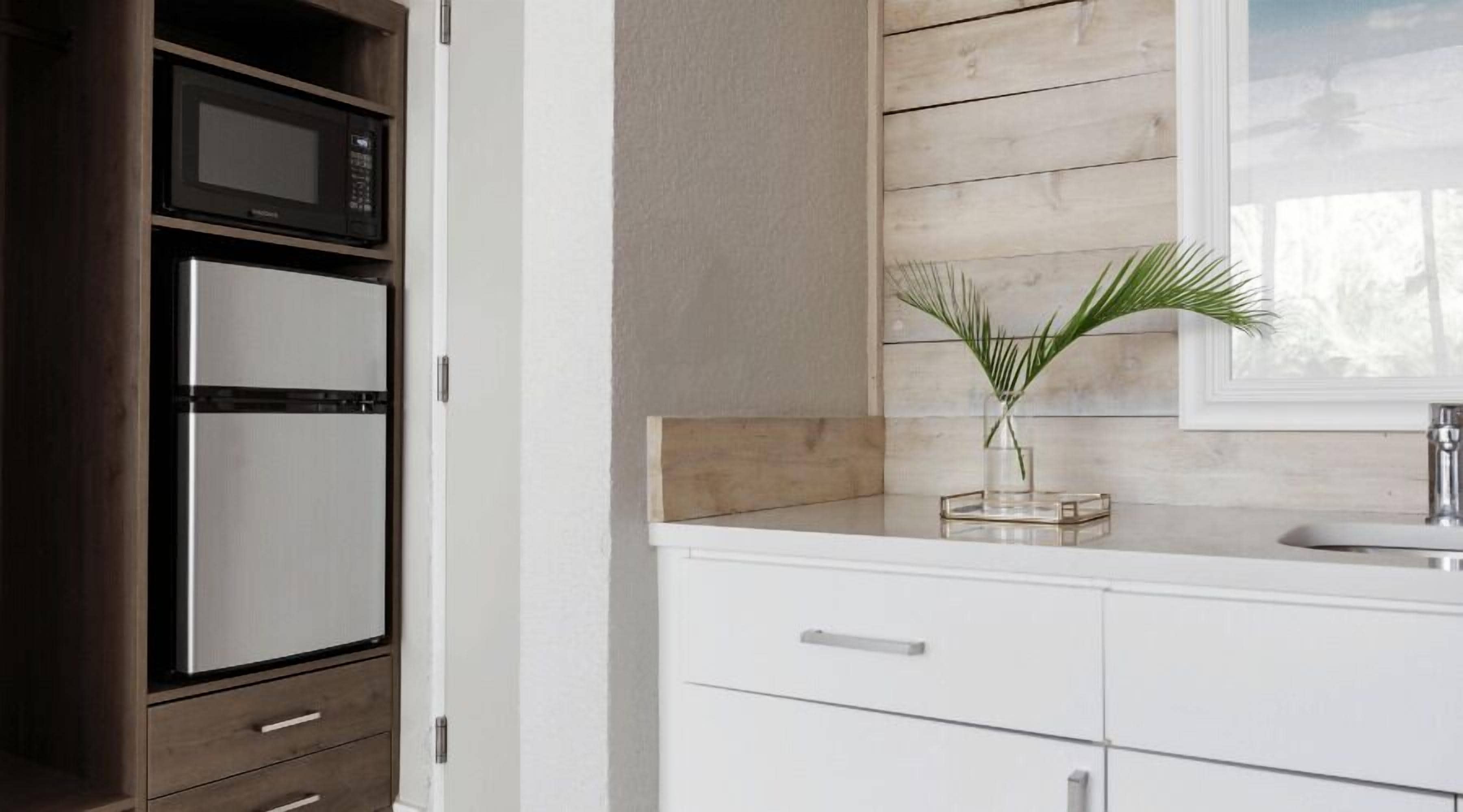 Une cuisine moderne dotée d’un four à micro-ondes encastré, d’une armoire blanche et d’un pare-feu en bois.