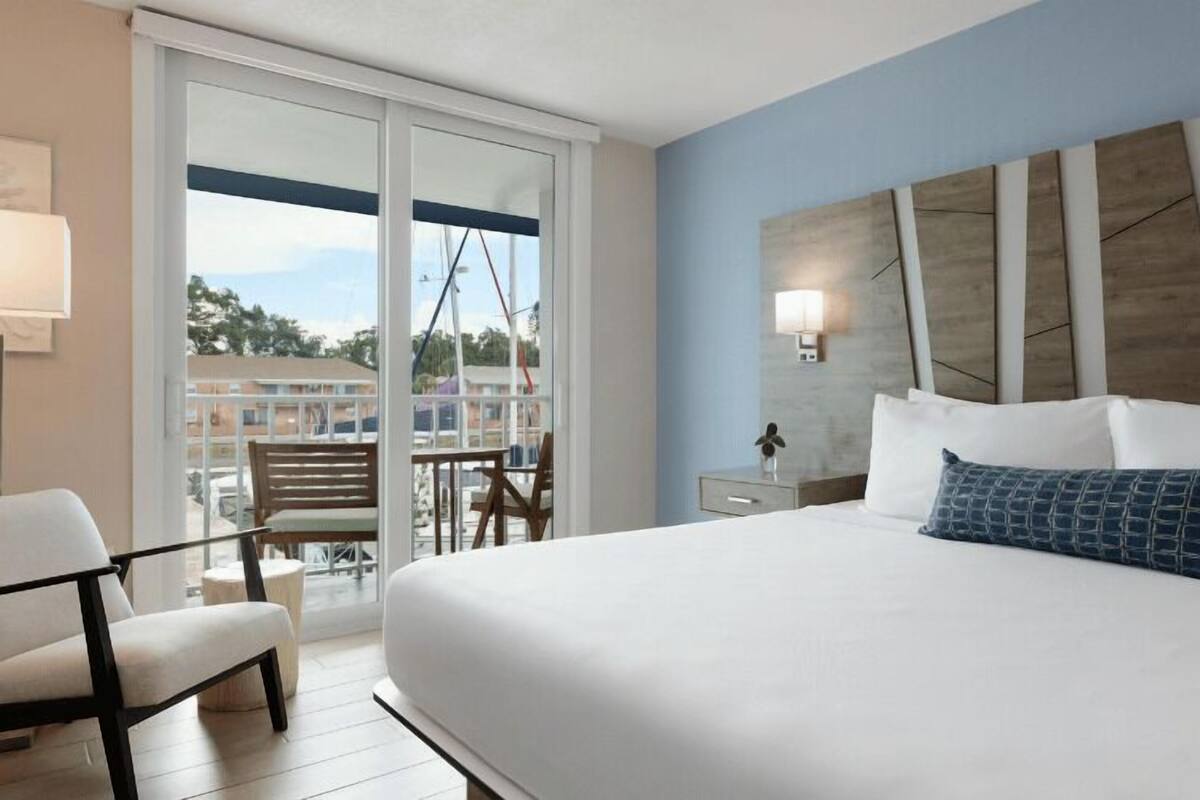 Een hotelkamer met een groot bed, een balkon met uitzicht en een modern hoofdeinde.