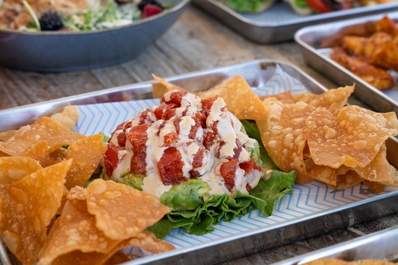 A tray of nachos with cheese, lettuce, and a red sauce.