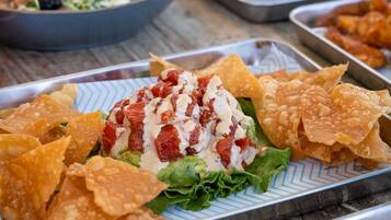 A tray of nachos with cheese, lettuce, and a red sauce.