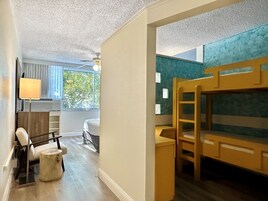 Una habitación con literas, un escritorio, una silla, una lámpara y una ventana con cortinas.