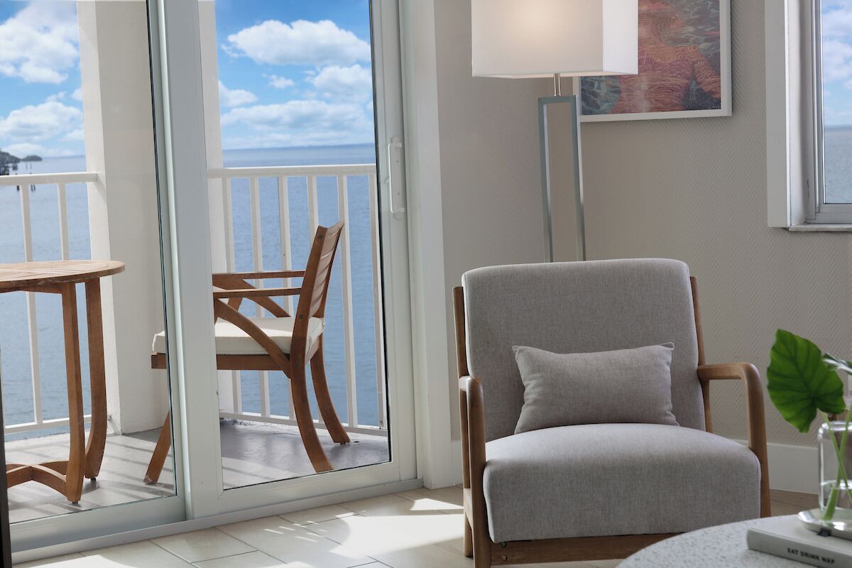 Una habitación con vista al mar, una silla, una mesa y una lámpara.