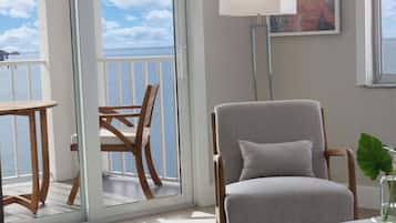 Una habitación con vista al mar, una silla, una mesa y una lámpara.