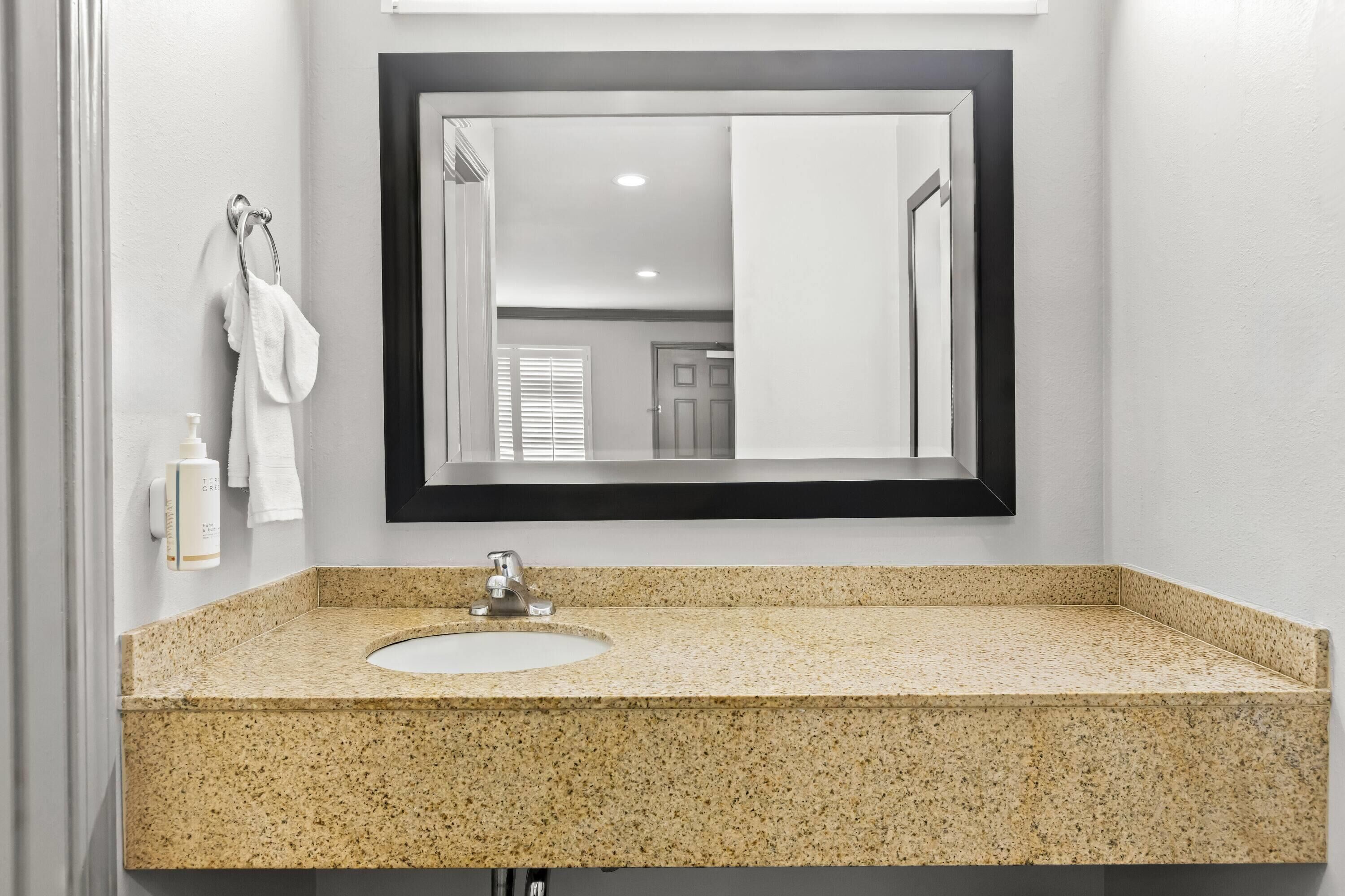 Une salle de bain avec un lavabo à vasque en granit, un miroir et un porte-serviettes.