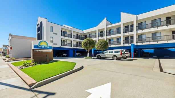 Een Days Inn hotel met een duidelijke oprit, een parkeerplaats en een bord met het adres.