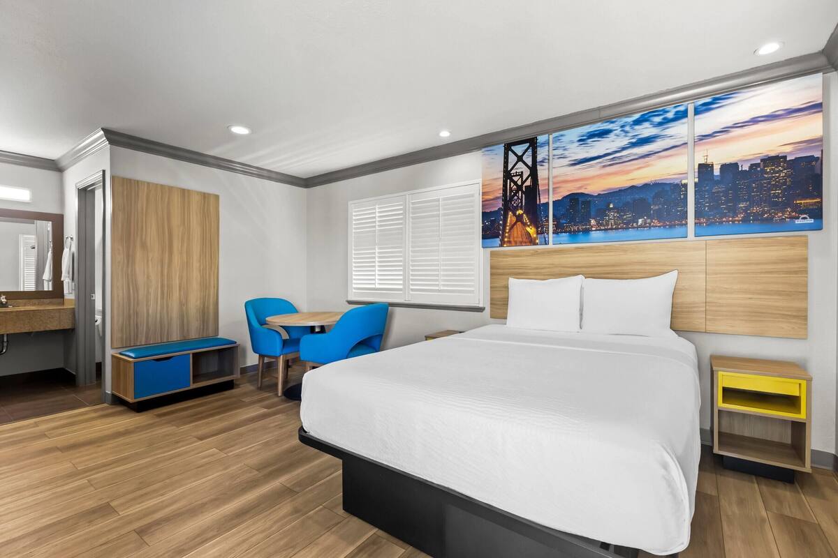 Une chambre d’hôtel moderne dotée d’un grand lit, d’un bureau, d’une chaise et offrant une vue sur le paysage urbain.