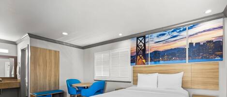 A modern hotel room with a large bed, a desk, a chair, and a cityscape view.